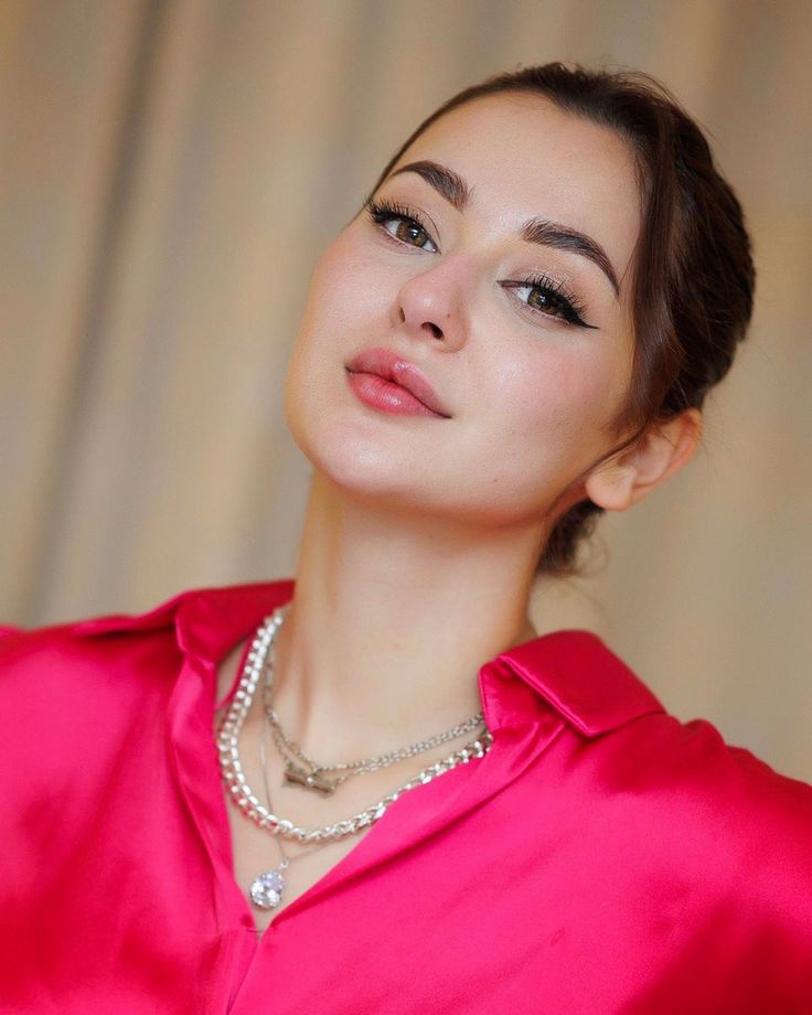 a woman wearing a pink shirt and pearls on her necklace is posing for the camera