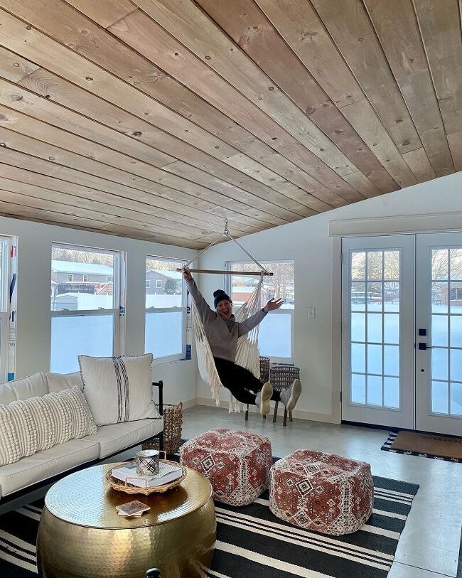 a man in a hammock hanging from the ceiling above a living room filled with furniture