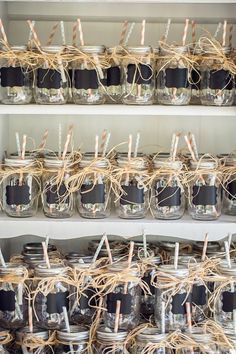 mason jars are lined up on shelves with twine and tags tied to the lids