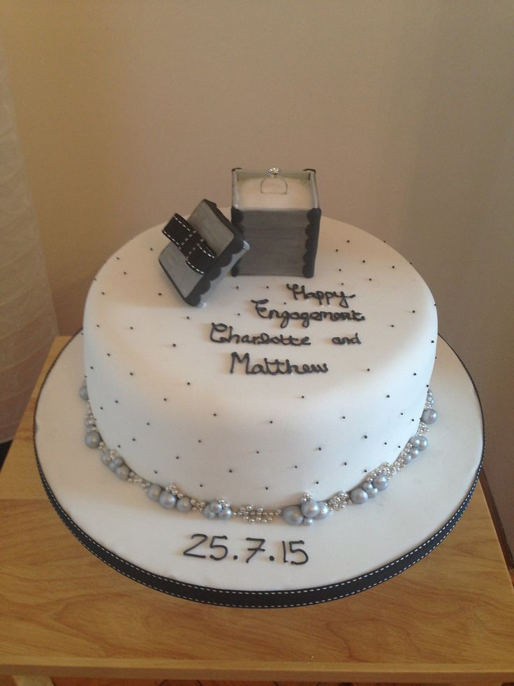 a white cake with pearls and a camera on top that says your first engagement and marriage