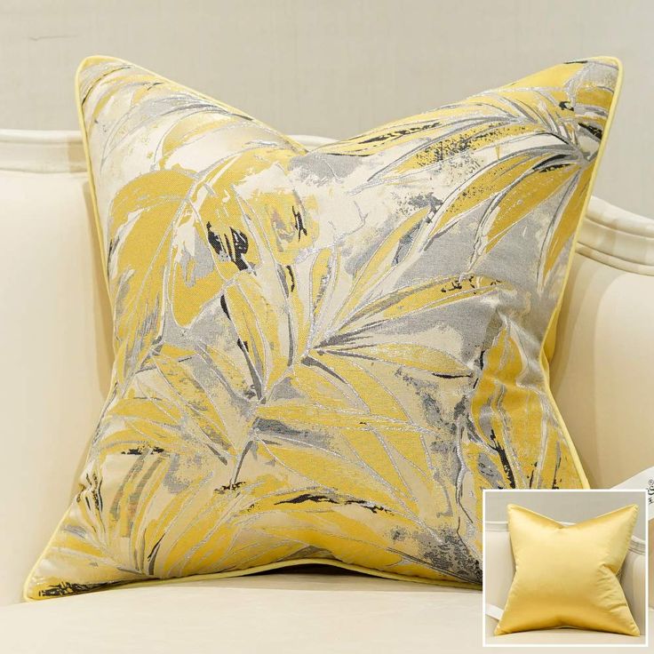 a yellow and grey pillow sitting on top of a white couch