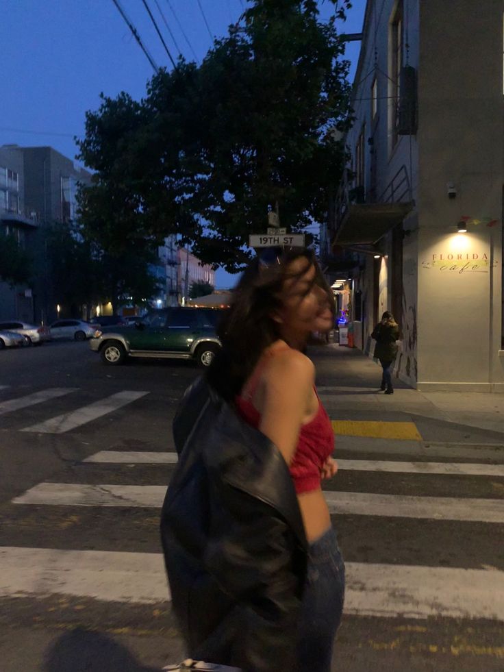 a woman riding a skateboard down a street at night with her back to the camera