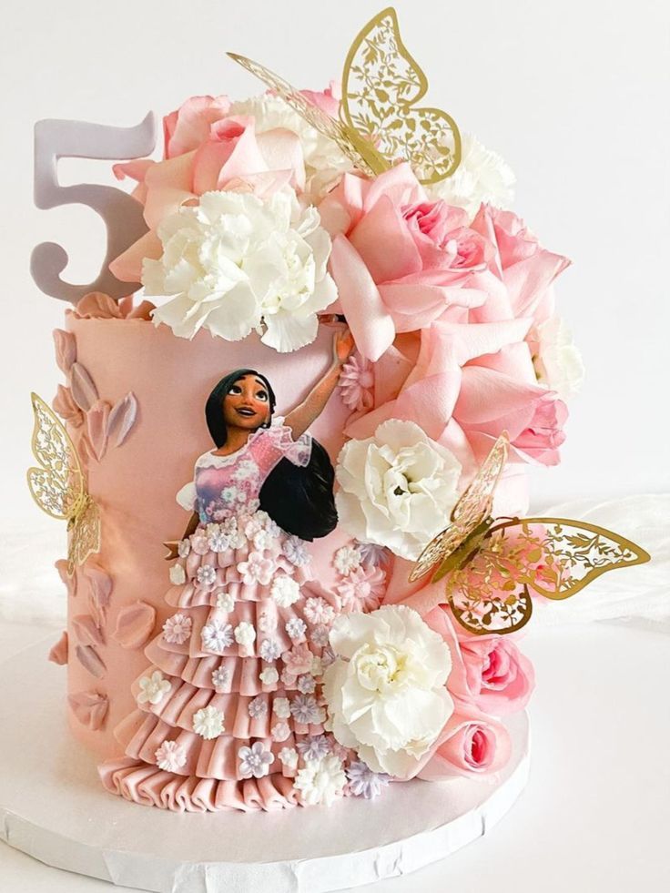 there is a cake decorated with flowers and a doll on the top one has a number five