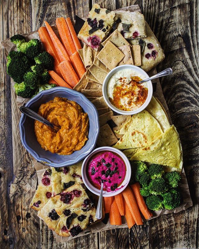 a platter with hummus, carrots, broccoli and crackers