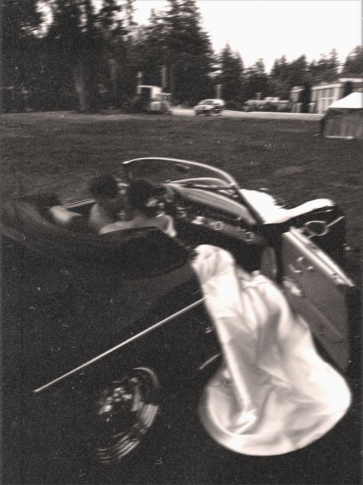 a black and white photo of an old car with the driver in it's seat