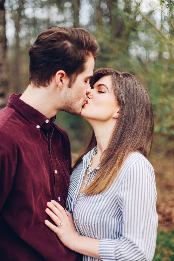 a man and woman are kissing in the woods with their noses close to each other