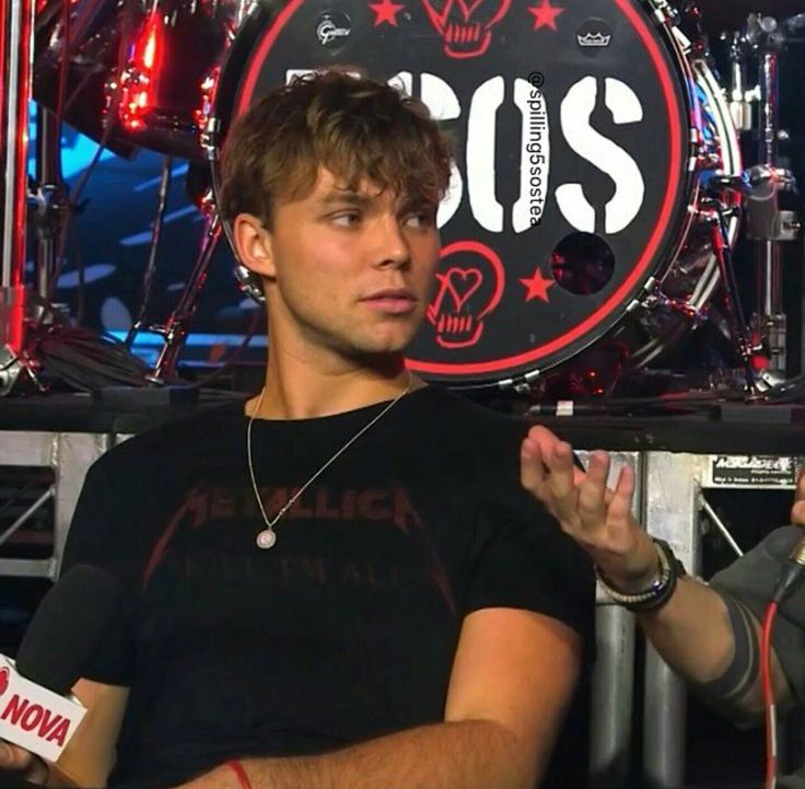 a young man sitting in front of a drum set on stage with two microphones