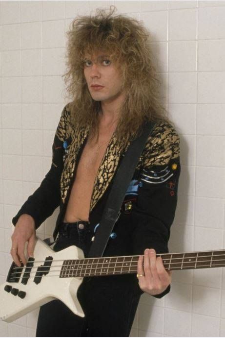 a man with long hair holding a white guitar