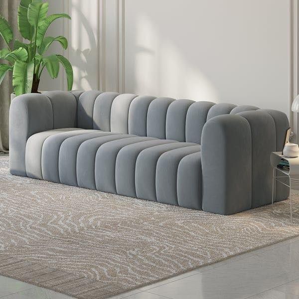 a large gray couch sitting on top of a rug in front of a potted plant