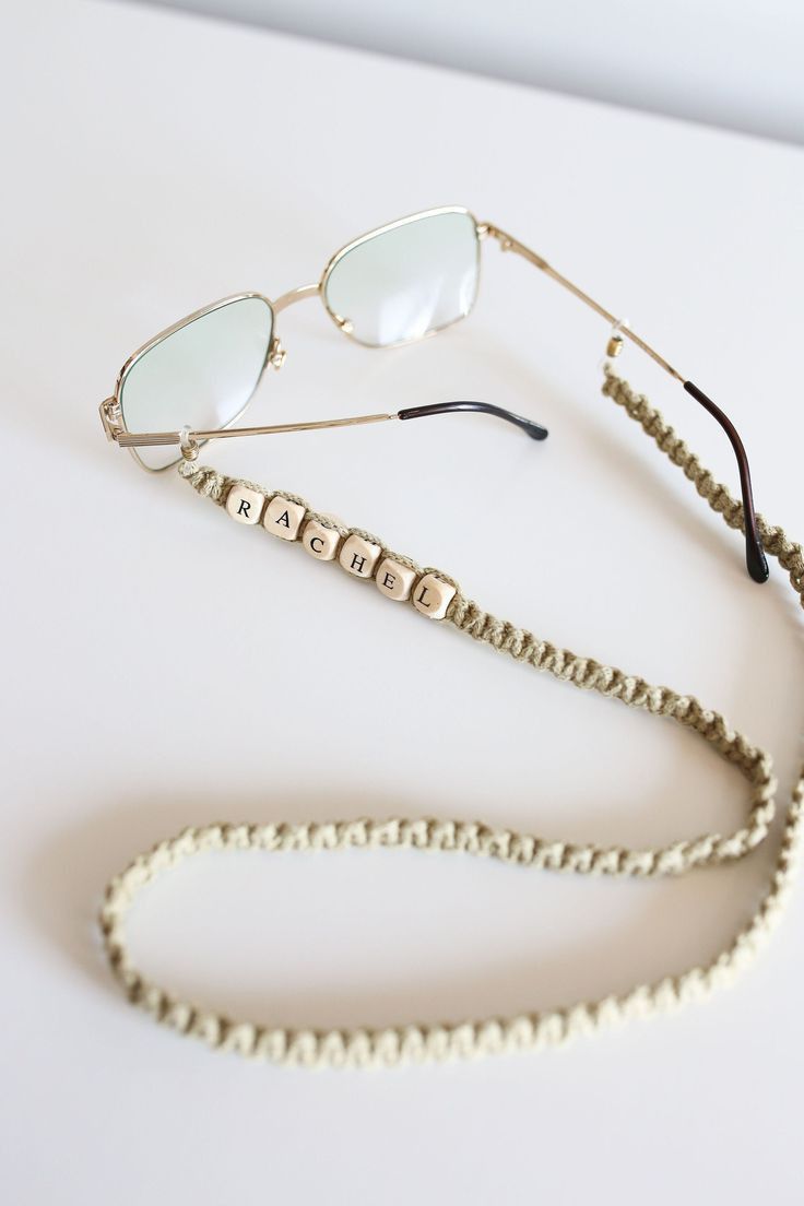 two pairs of sunglasses with beaded cord attached to them on a white table top