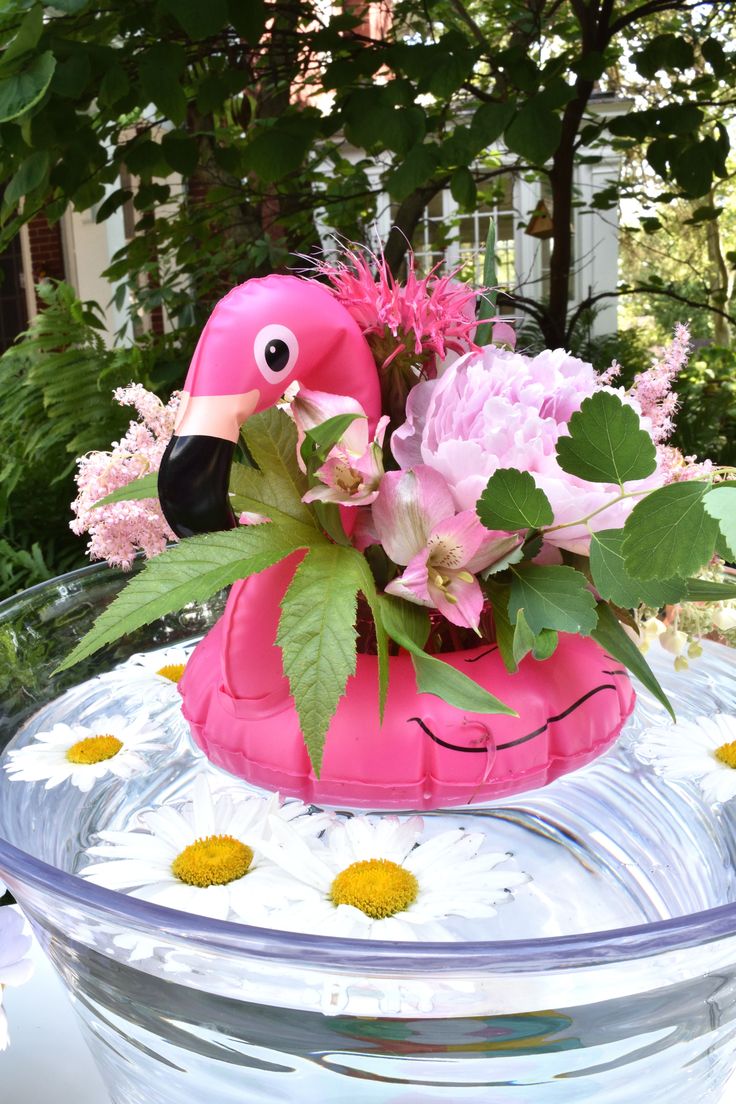 a pink flamingo planter sitting on top of a glass bowl filled with flowers