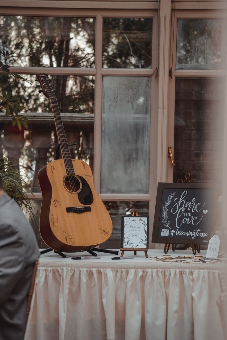 a wooden guitar sitting on top of a table next to a sign that says save love