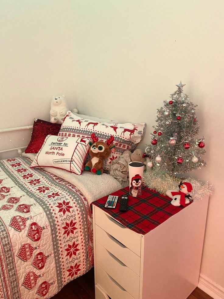 a bedroom decorated for christmas with a bed, nightstand and small tree in the corner