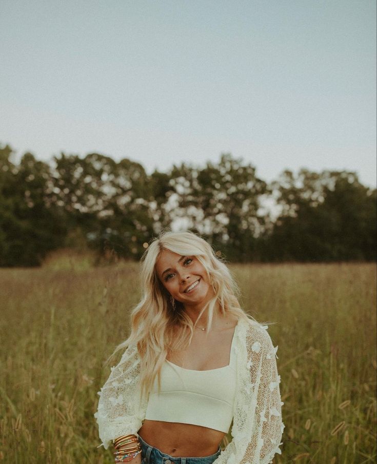 a woman standing in the middle of a field with her hand on her hip and looking off into the distance