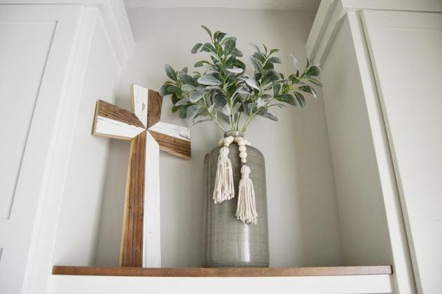 a vase with flowers and a cross on a shelf