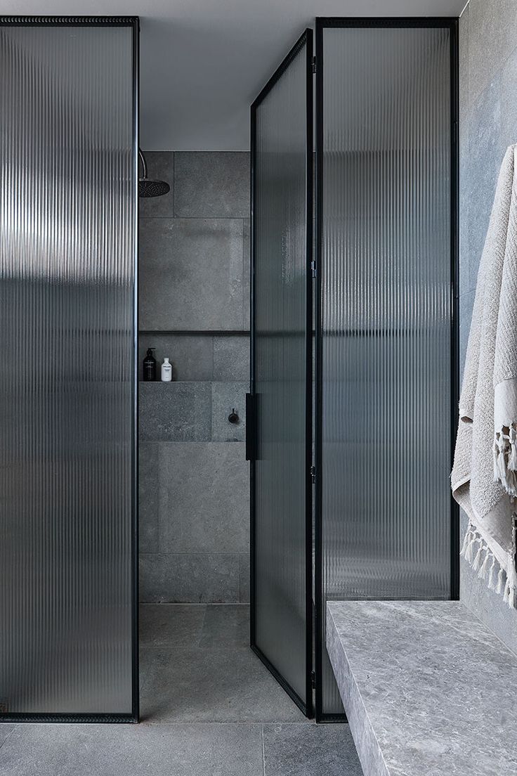 a bathroom with a glass shower door next to a white towel on a counter top