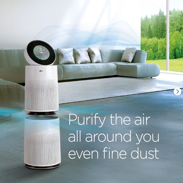 an air purifier sitting on top of a floor next to a couch