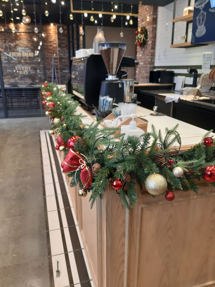 a counter with christmas decorations on it and lights hanging from the ceiling in an office