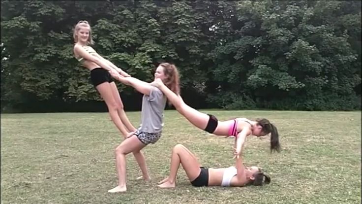 three girls are playing with each other in the grass while one girl is on her knees