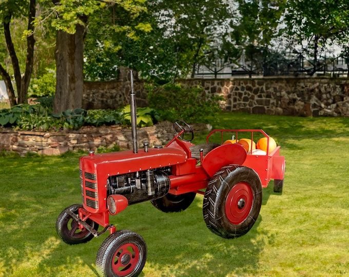 an old red tractor sitting in the grass