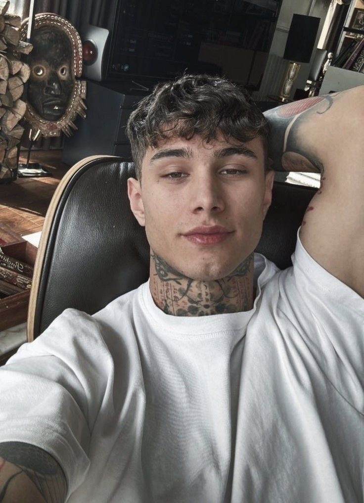 a man with tattoos sitting in a chair