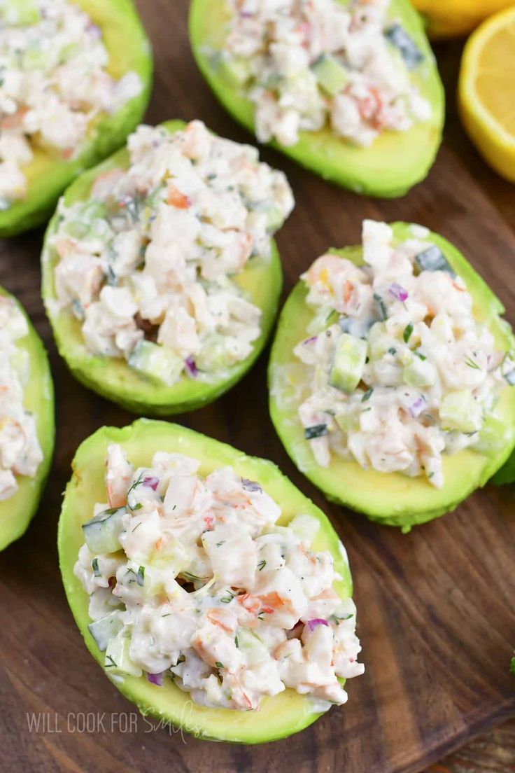 cucumbers stuffed with crab salad on a wooden cutting board next to lemons