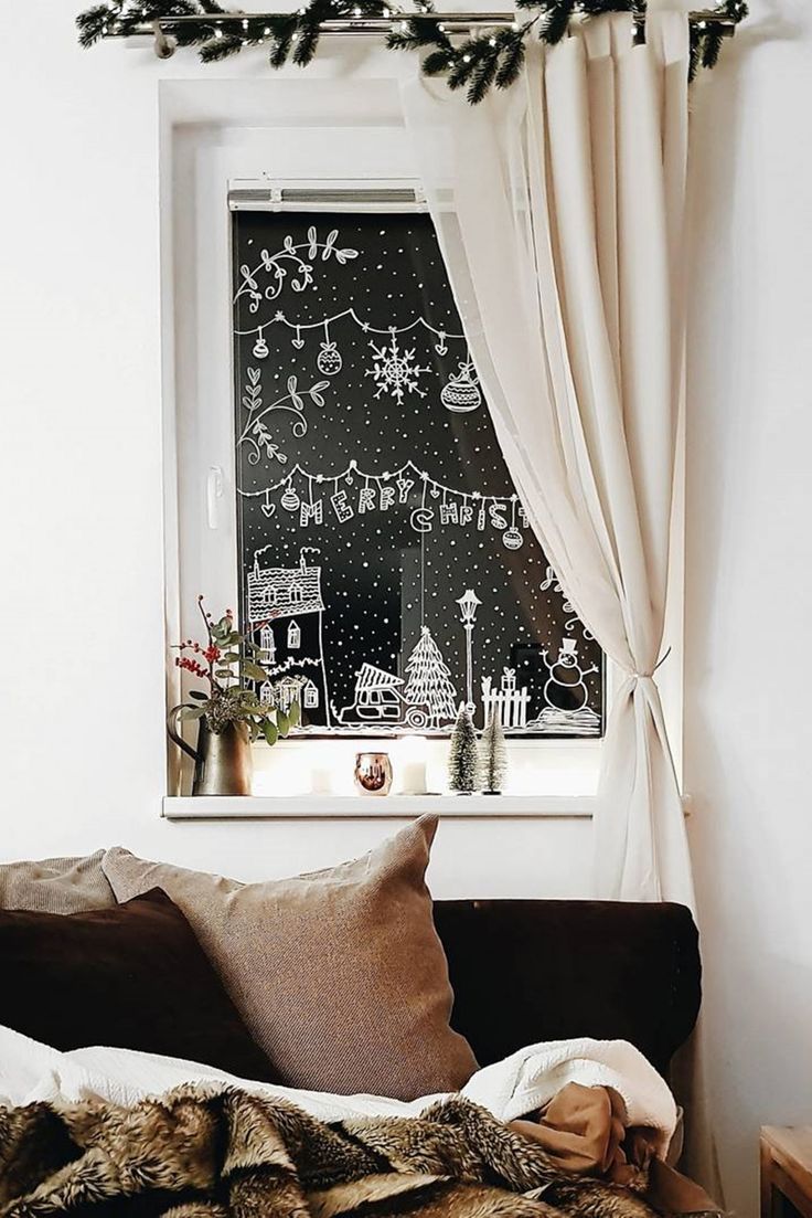 a bed with pillows and blankets in front of a window decorated with christmas lights on the windowsill