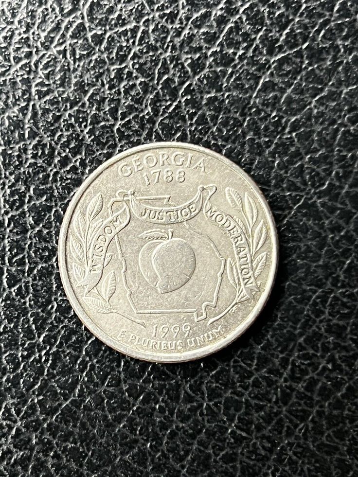 a close up of a coin on a black leather surface with the image of an apple