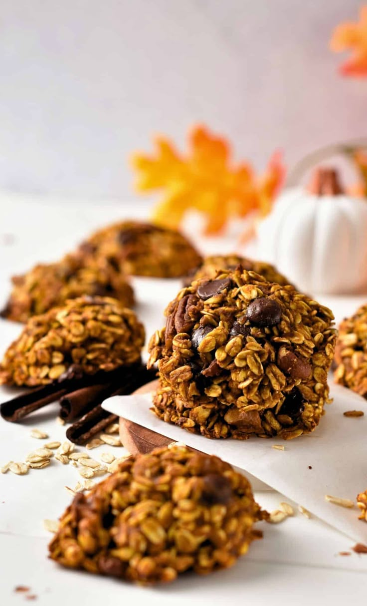 chocolate and oatmeal breakfast cookies on parchment paper with pumpkins in the background