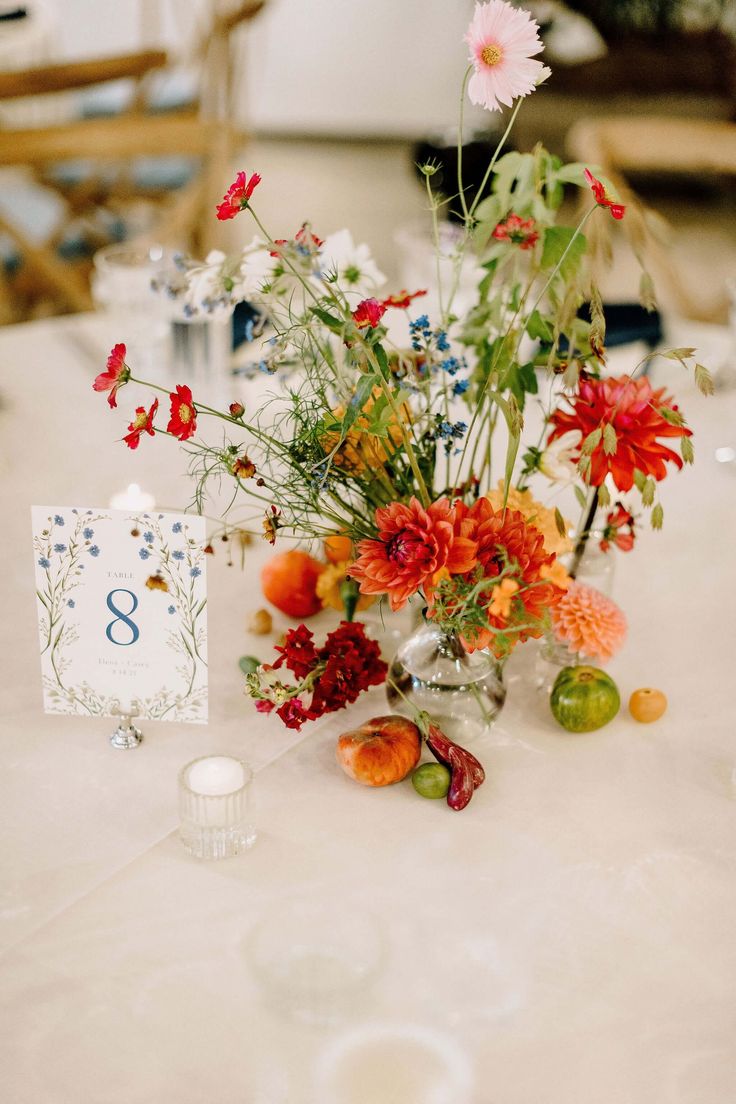 an arrangement of flowers and candles on a table at a wedding reception with the number eight