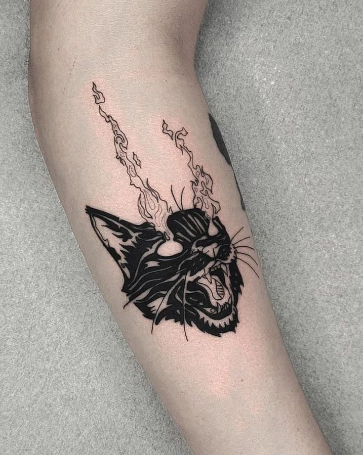 a black and white cat tattoo on the left arm with flames coming out of it