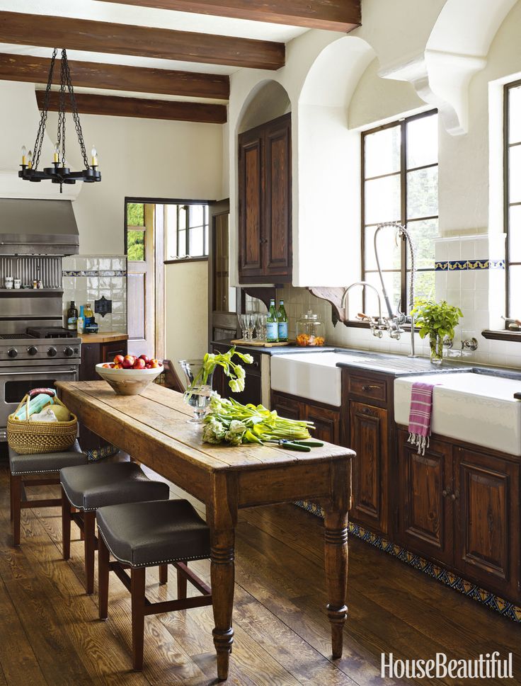 a large kitchen with wooden floors and white walls, along with an island table surrounded by black leather chairs