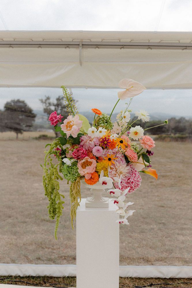 a tall white vase filled with lots of flowers