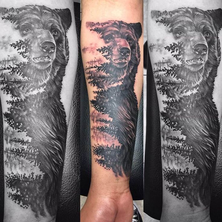 a man's arm with a bear and trees tattoo on it