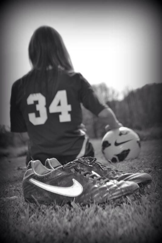 a woman sitting on the ground with a soccer ball in front of her and wearing a jersey that says 34