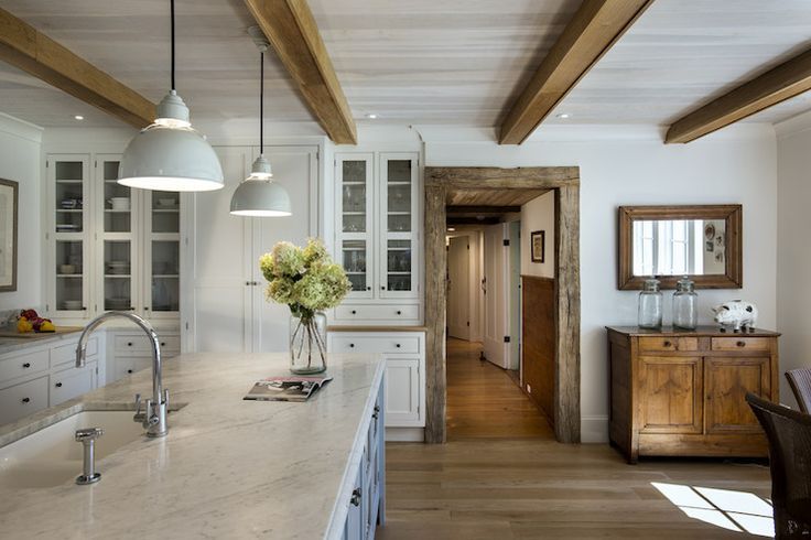 a large kitchen with white cabinets and wooden beams on the ceiling, along with marble counter tops