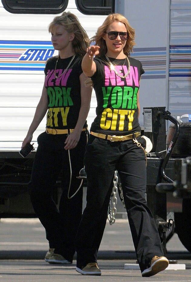 two women in matching shirts are walking down the street