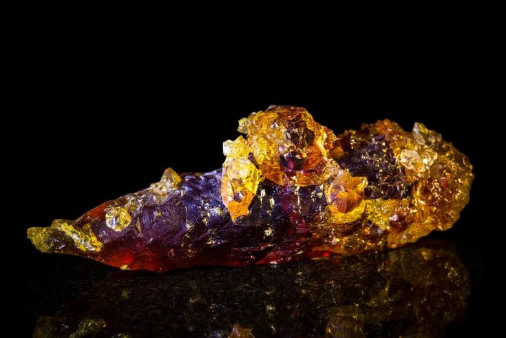 a piece of colorful rock sitting on top of a black surface