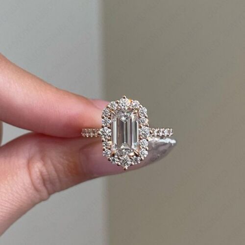 a woman's hand holding an emerald and diamond engagement ring with diamonds around it