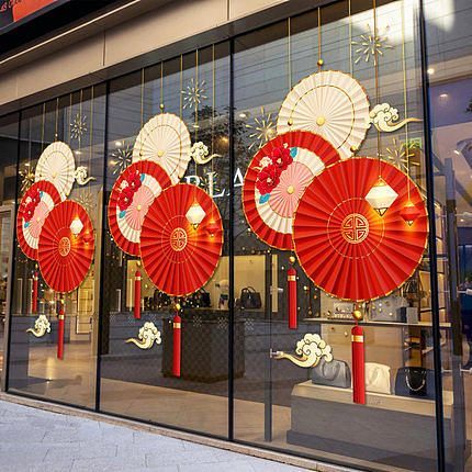 a storefront with red and white decorations on the front glass windows, along with chinese lanterns