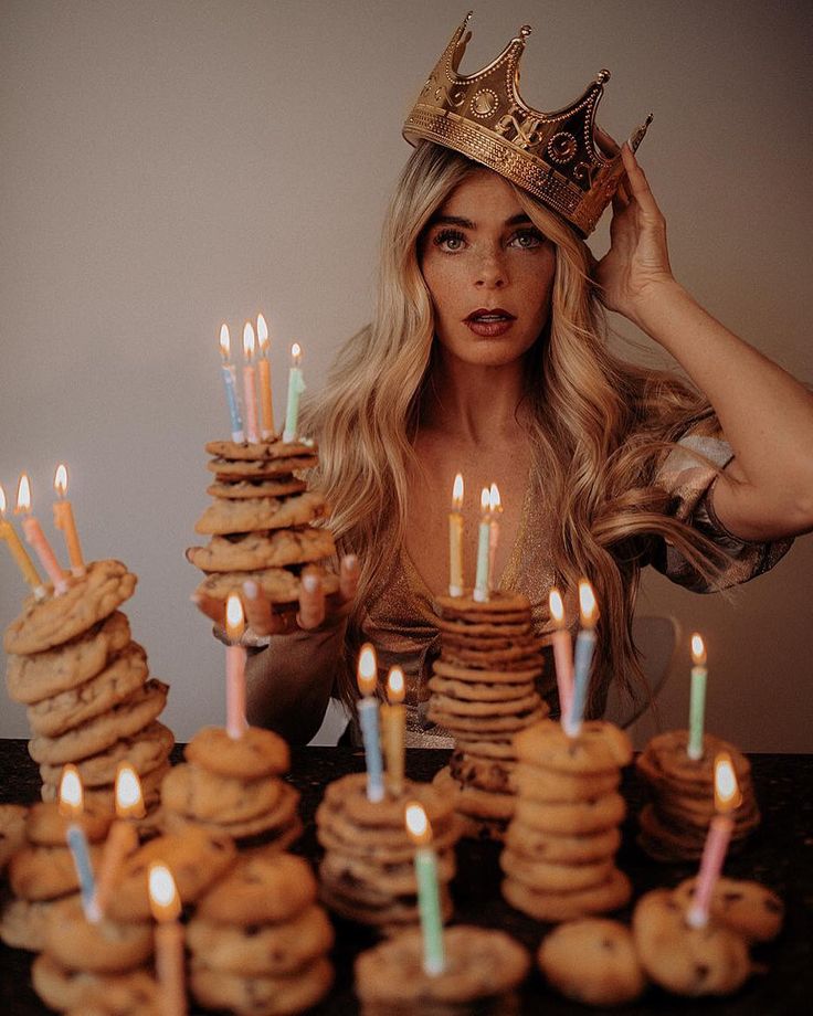 a woman wearing a crown is surrounded by cookies and lit candles