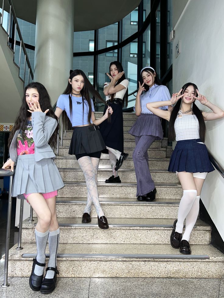 the girls are posing on the stairs in their school uniforms and skirts, with one girl holding her hand up to her face