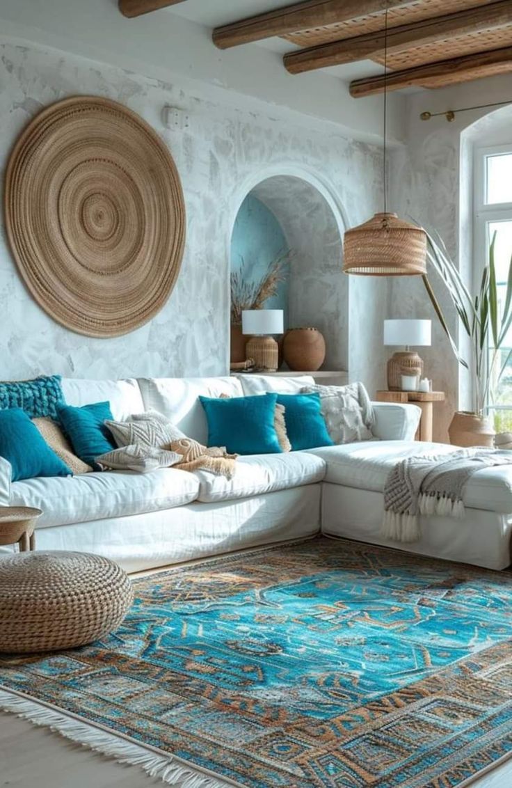 a living room filled with lots of white furniture and blue pillows on top of a rug