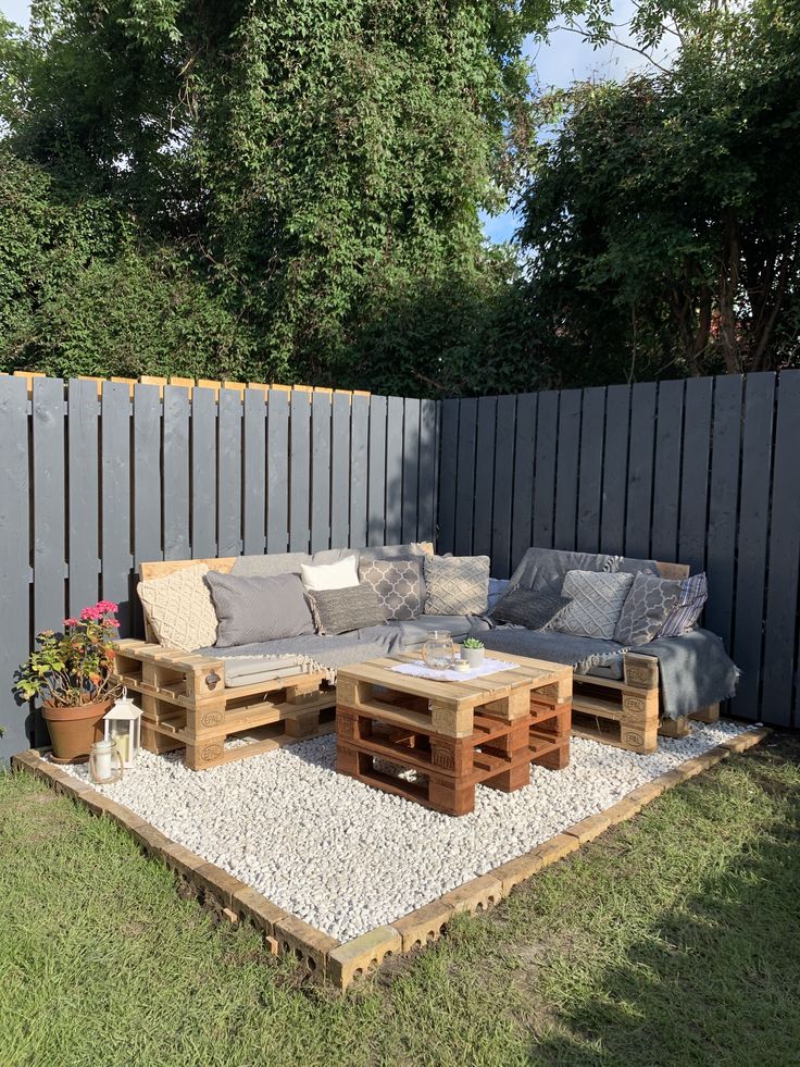 an outdoor seating area made out of pallets and wooden crates with gravel on the ground