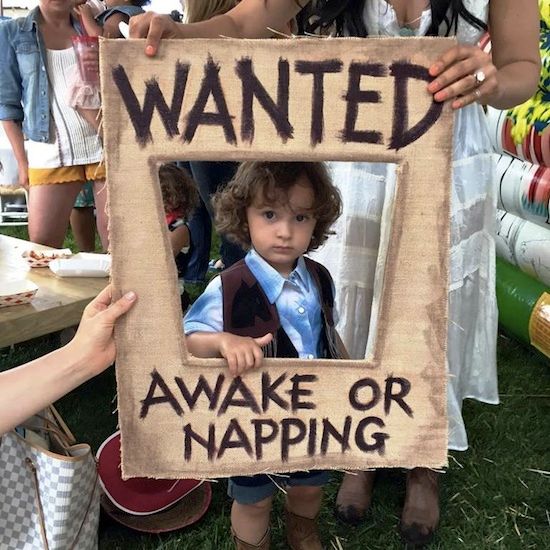 a young boy holding up a sign that says wanted awake or napping on it