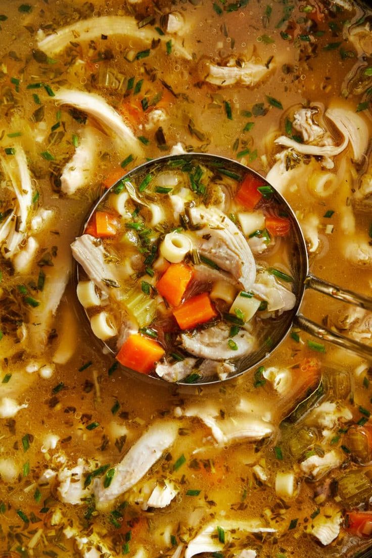 a spoon full of soup with chicken and carrots