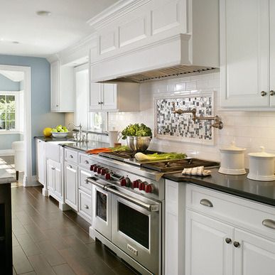 a kitchen with white cabinets and stainless steel appliances, along with an island countertop