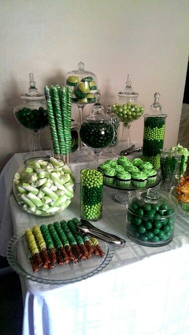 a table topped with lots of candy and green candies next to desserts on plates