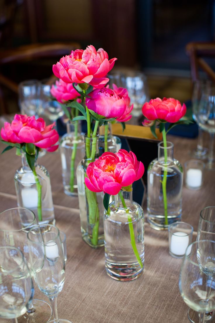 pink flowers in vases on a table with candles and glasses around the tablescape