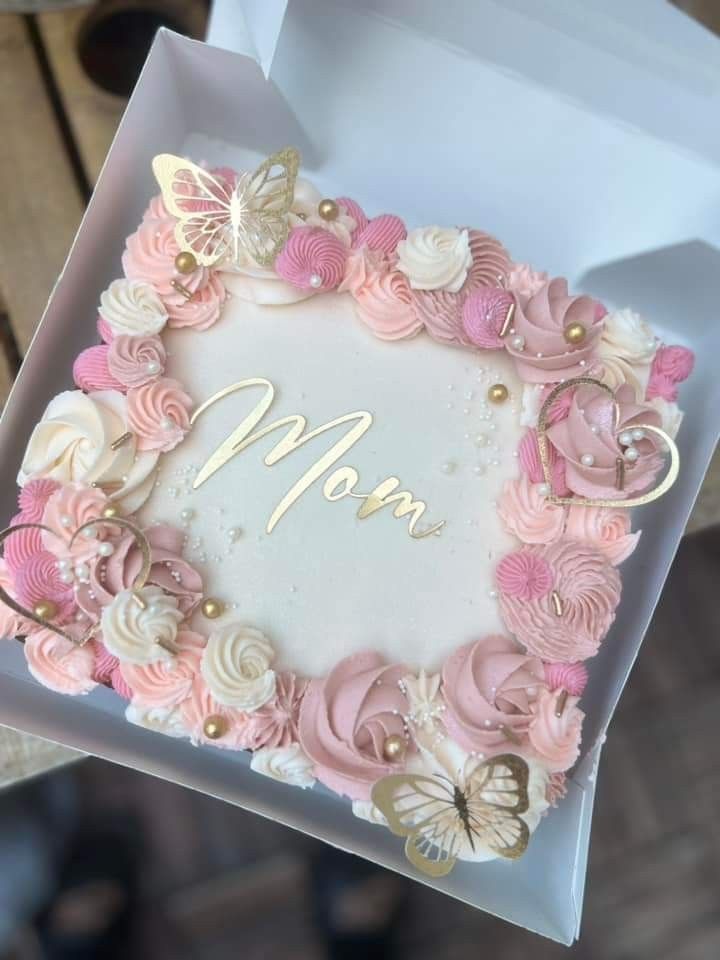 a mother's day cake with pink and white frosting flowers in a box